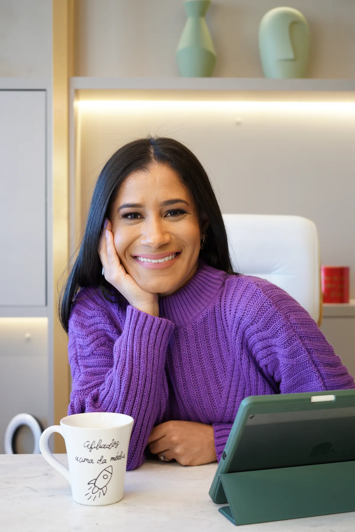 Fábia Almeida sorrindo em uma mesa com tablet